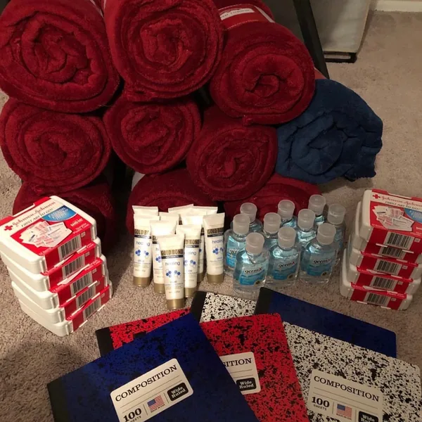 Red fleece blankets, first aid kits, lotion, hand sanitizer and notebooks set out for donation