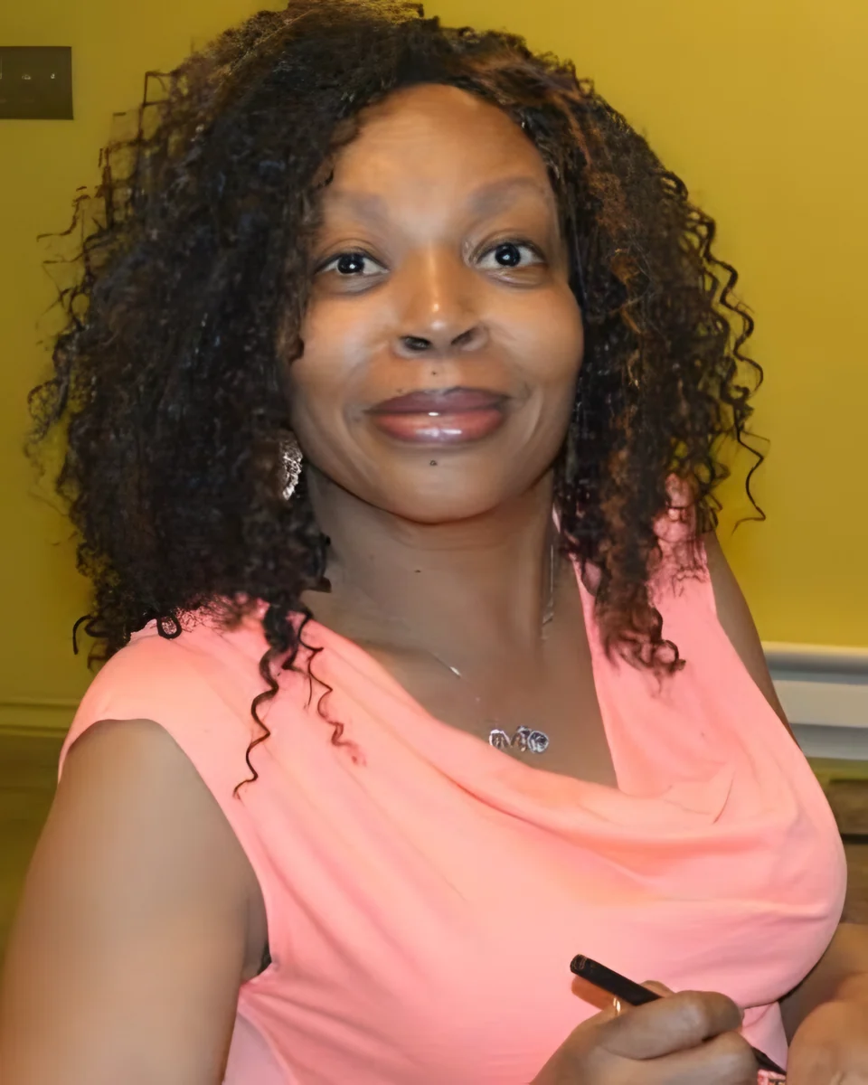 Glendra Ruffin-Raymond, smiling, in a pink top